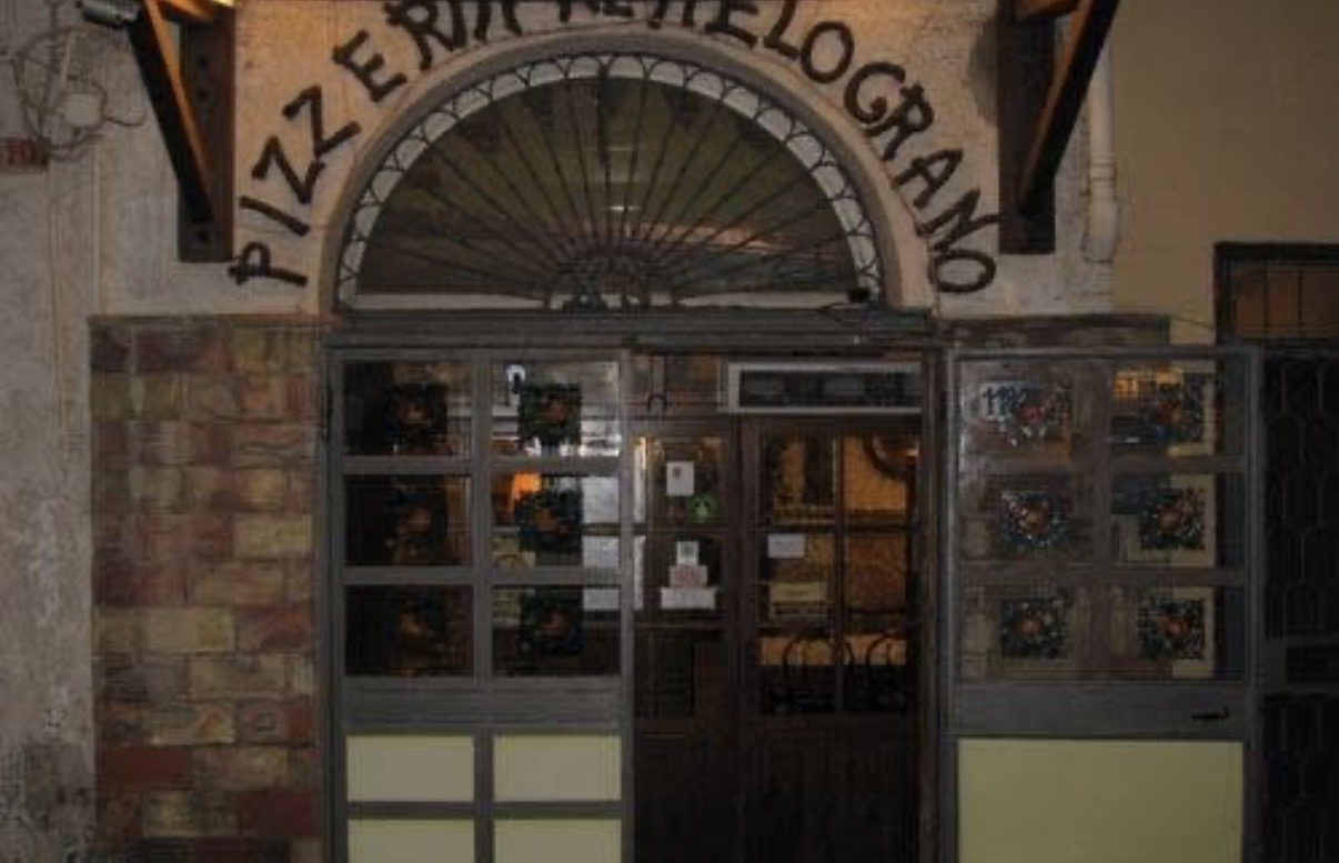 Ingresso storico della Pizzeria Al Melograno, con l'insegna in ferro battuto sopra la porta